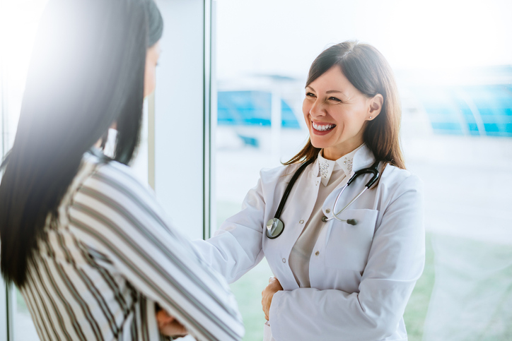 Woman doctor speaking with patient success story.