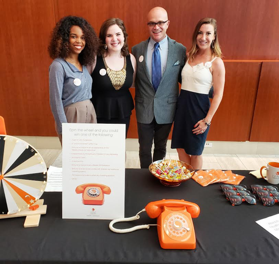 Four members of Team Lenz (Anna Laura, Jon Waterhouse, Christine Mahin, and Nicole Watson) smiling behind the Lenz table at the Top Docs reception.