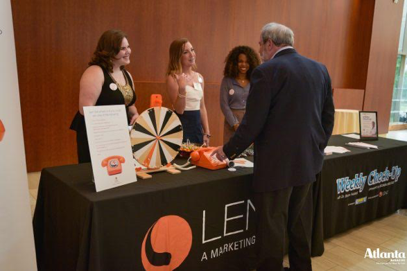 Team Lenz Members Nicole Watson, Christine Mahin, and Anna Laura speak with a Toc Docs at the Lenz table.