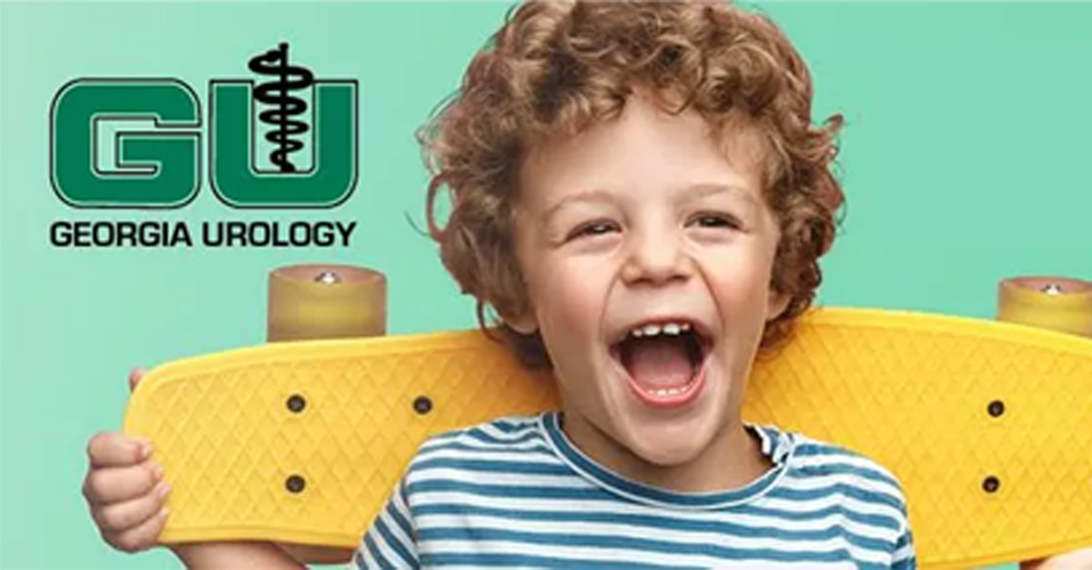 A happy, young boy holding a yellow skateboard with a Georgia Urology logo beside him