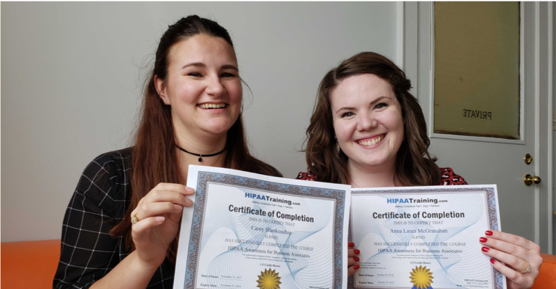 Two Lenz team members, Anna Laura and Carey, hold up their certifications. 