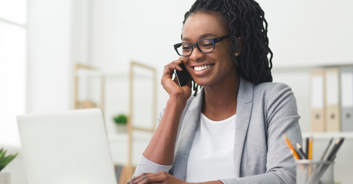 African American Business Woman Having Phone Conversation Working On Laptop In Modern Office, discussing how to use social media to build your personal brand.