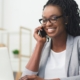 African American Business Woman Having Phone Conversation Working On Laptop In Modern Office, discussing how to use social media to build your personal brand.
